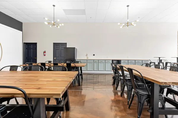 Kitchenette wall with sage cabinets, with tables in the foreground