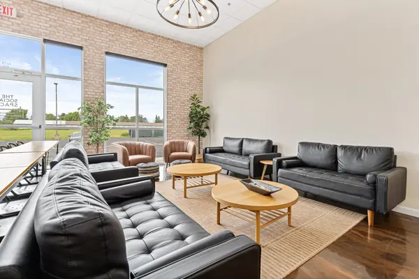 Close-up of black sofas, round coffee tables and cognac accent chairs by the brick wall