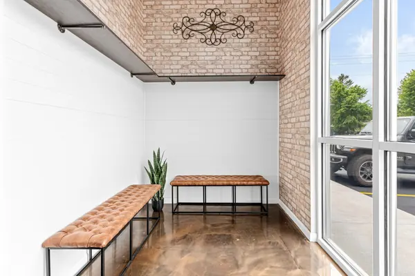 Entry alcove with two tufted leather benches, brick and a coat shelf