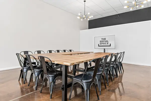 Long wood table with chairs, TV and black accent wall under a sputnik chandelier