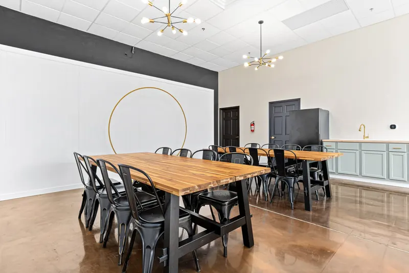 Long oak tables in front of the gold-ring backdrop wall