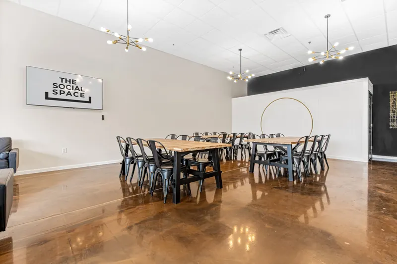 Long oak tables arranged facing the TV and backdrop wall
